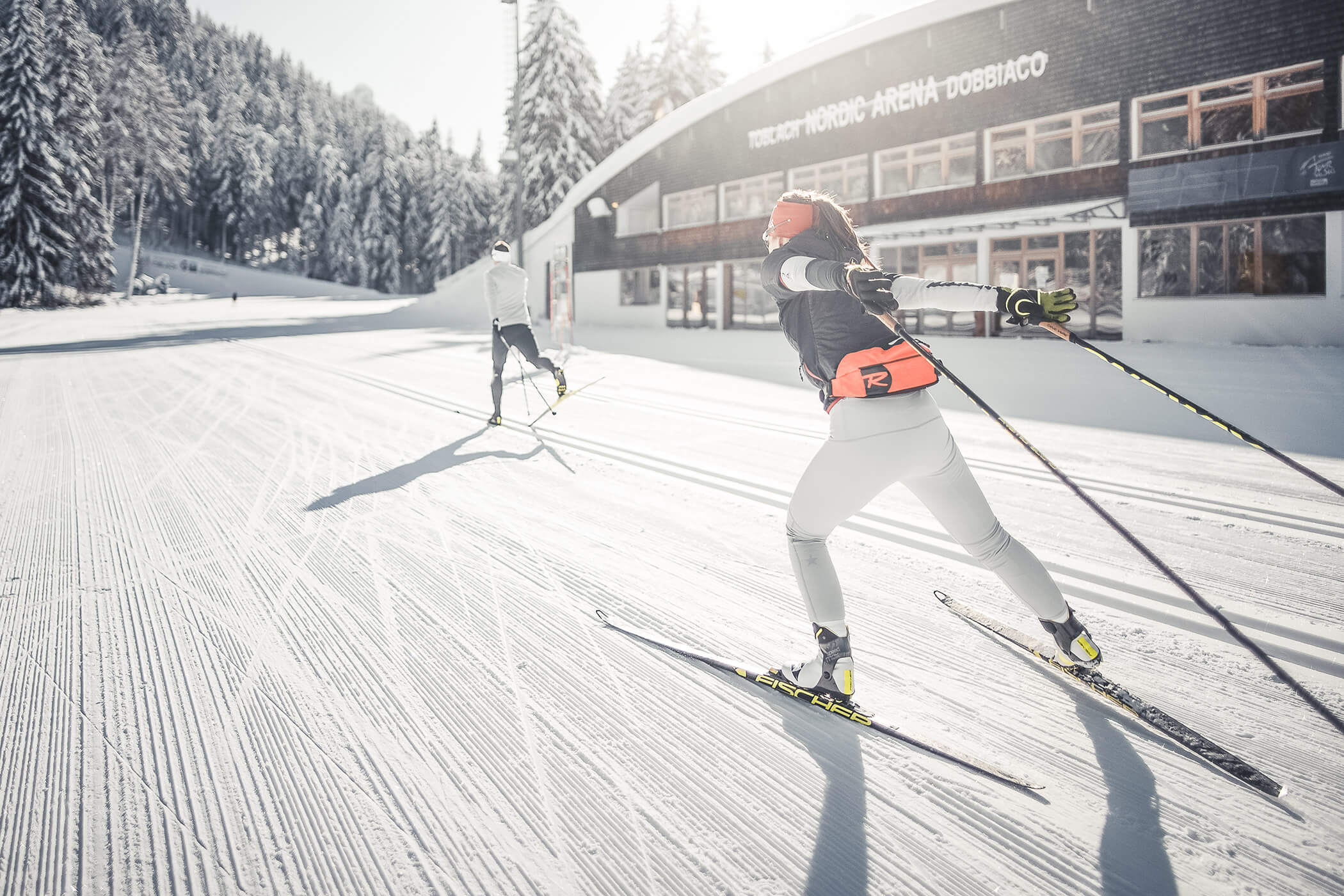 Two cross-country skiers on the slope of the Nordic Arena in Dobbiaco - Laurin's