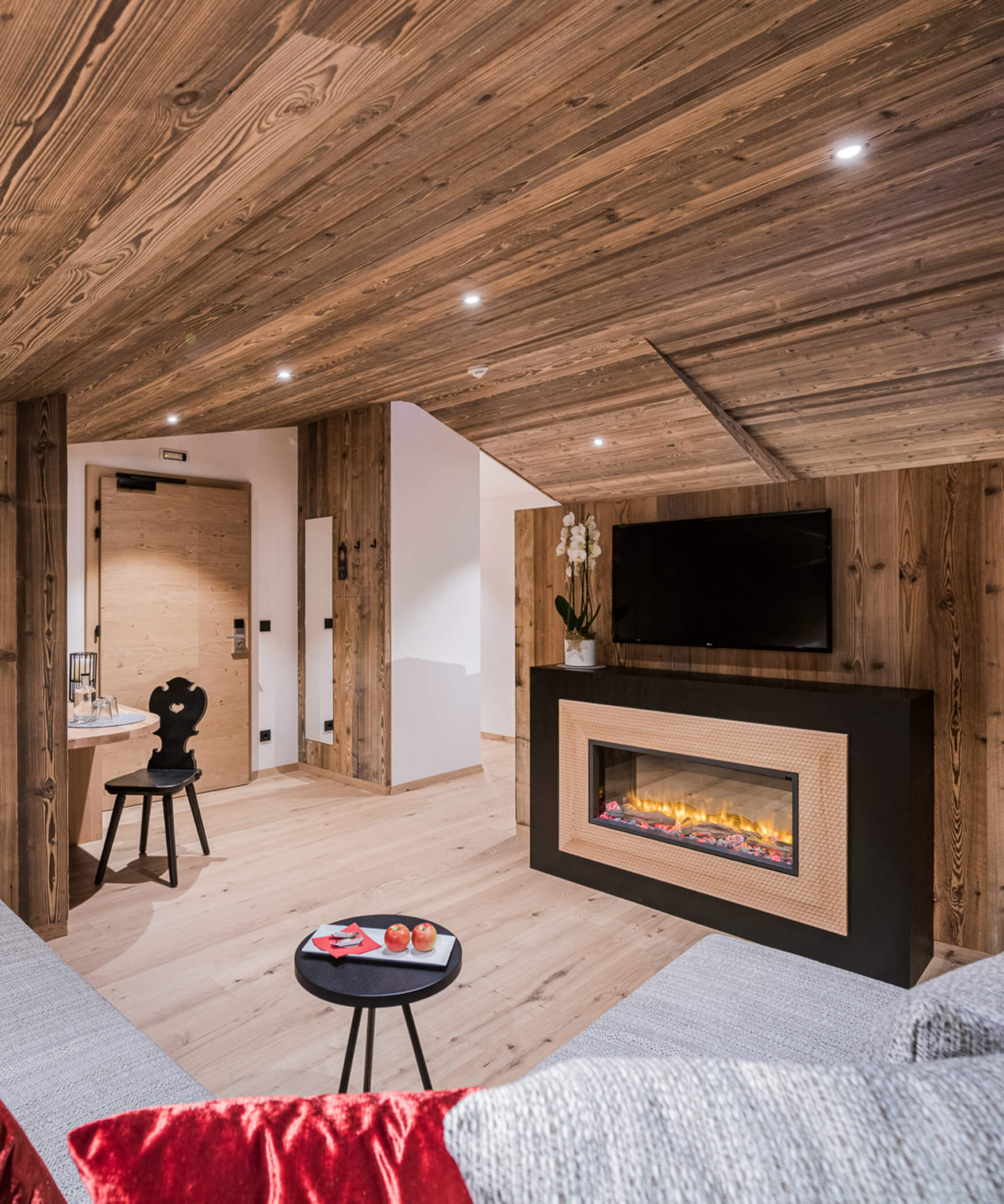 Wohnzimmer der Chalet Suite mit brennendem Ofen und einem grauen Sofa - Laurin's