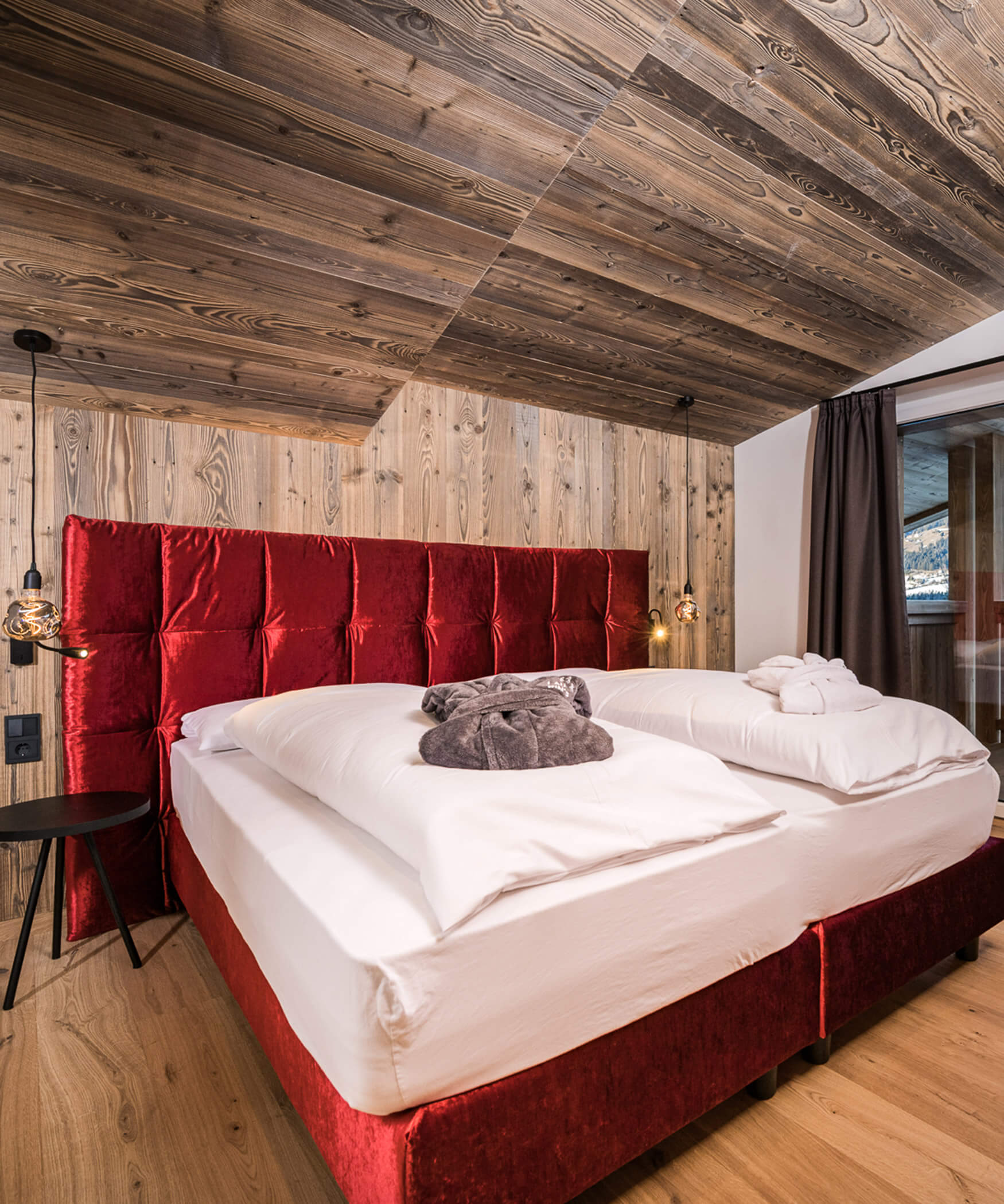 Schlafzimmer mit rotem Doppelbett der Chalet Suite - Laurin's