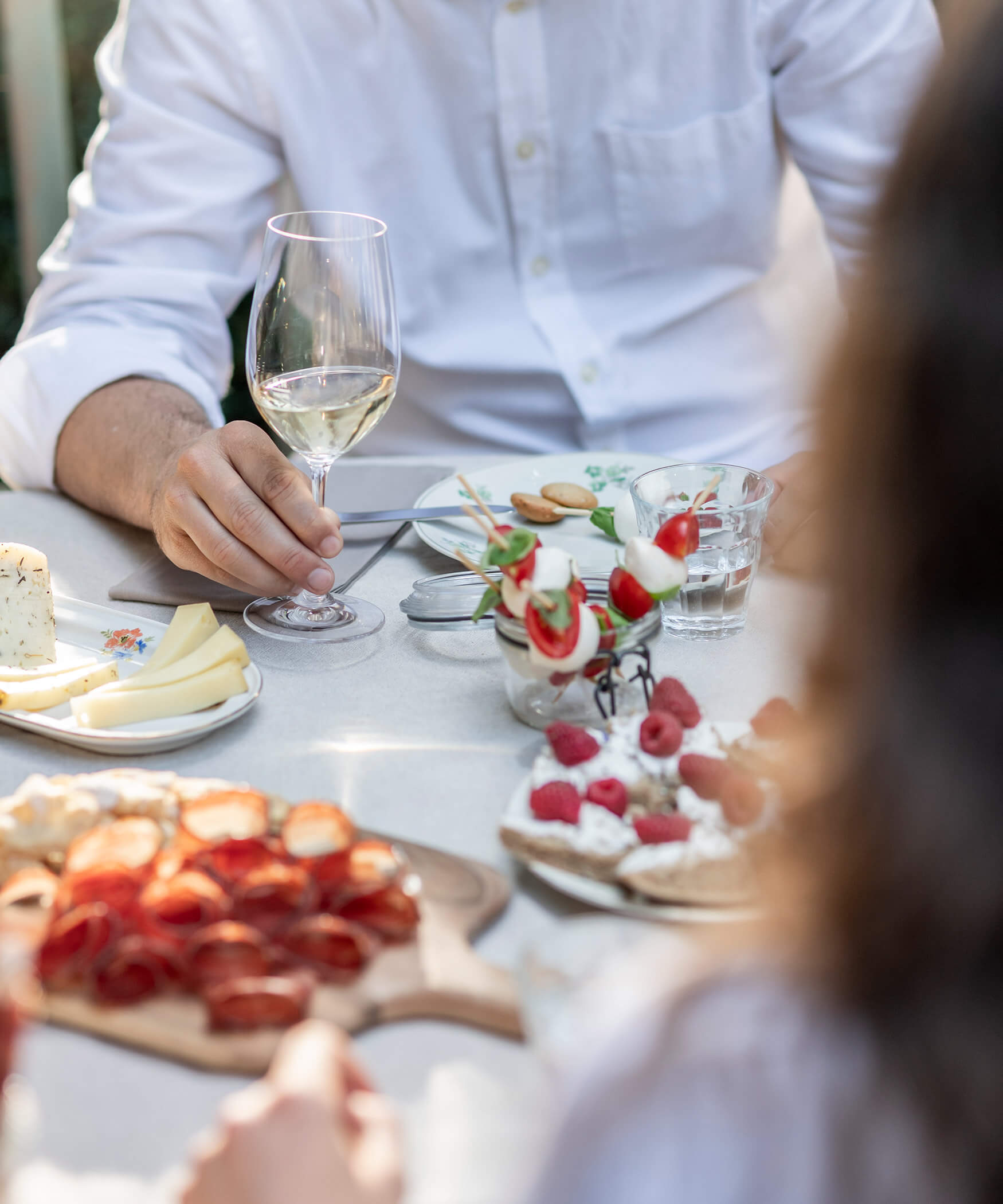 Una coppia a colazione, sul tavolo un piatto di formaggi e salumi, spiedini di pomodoro e mozzarella e una torta con lamponi - Laurin's