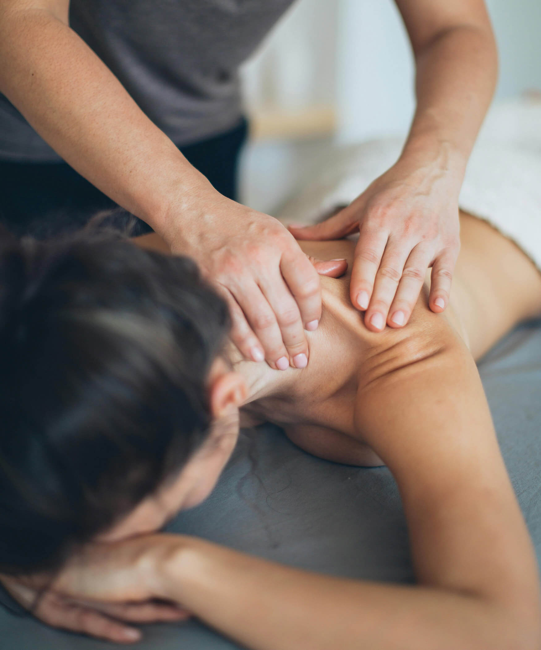 Una donna con i capelli castano scuro si sdraia su un lettino e si fa massaggiare - Laurin's